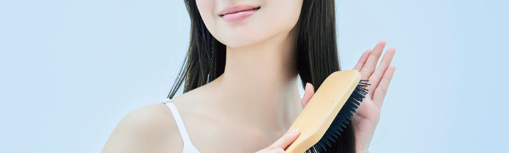 ヘアブラシで髪をとく女性の画像